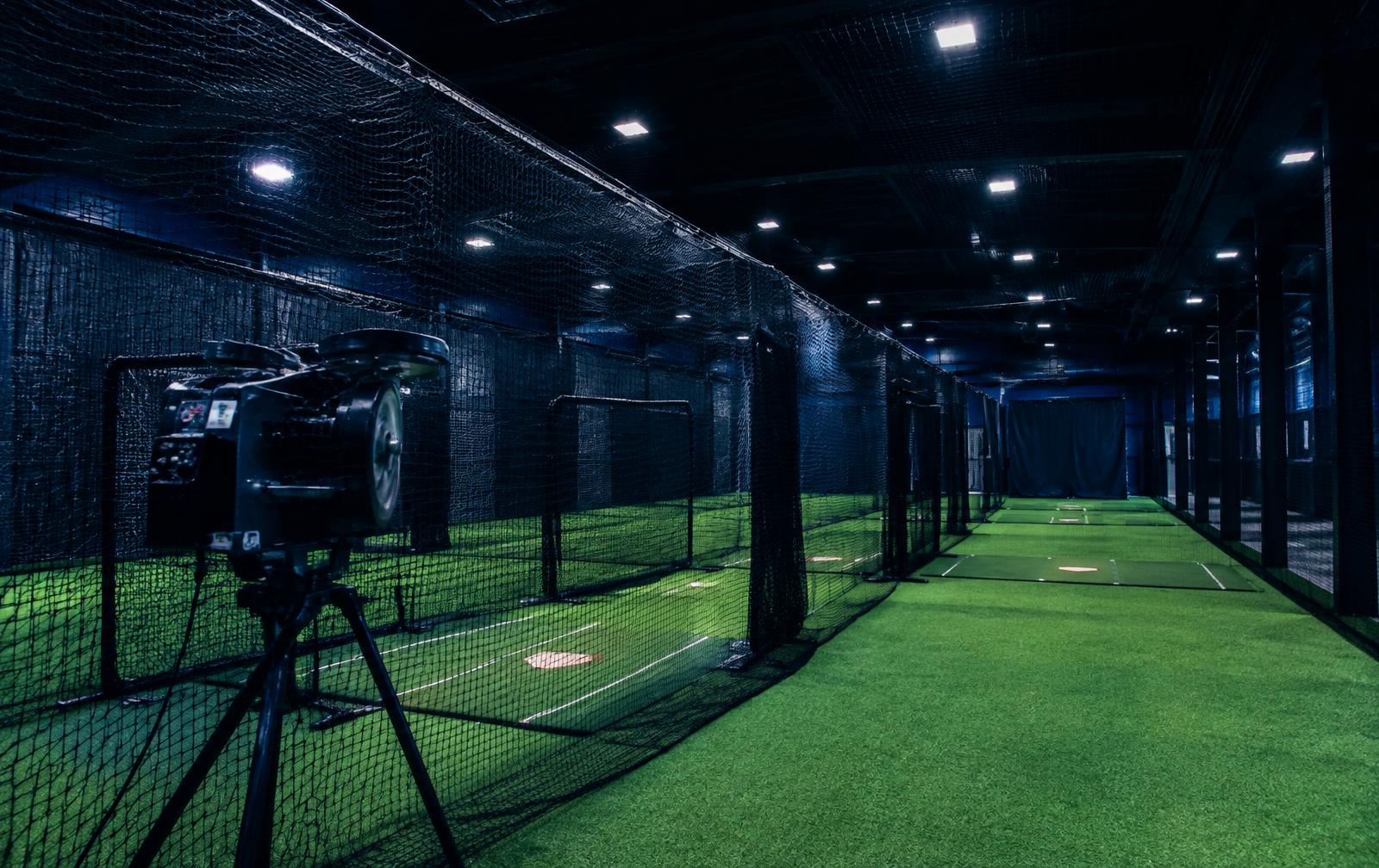 Row of indoor batting cages with turf